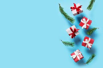 Polka dot pattern red gift box with ribbon and green tree branch falling on blue background