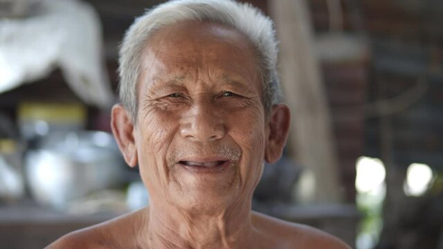 White-haired Asian elderly man do not wear clothes because of hot weather, poor status, older than seventy are laughing happily.