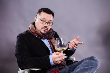 Solid cheerful man in kerchief sitting with glass of wine