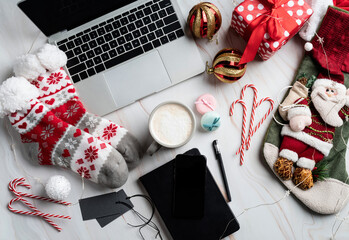 Fototapeta na wymiar Christmas desktop with laptop, tablet and smart phone surrounded by stockings, candy canes and coffee, top view flat lay