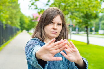 A young girl stretches her hand forward with an open palm as a STOP sign. The concept is irritation...