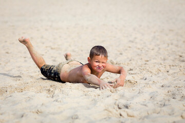 Young cute boy having fun on sand beach. © idea_studio