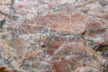 High granular texture of natural granite with color stains and small details on the surface in light blur with soft focus