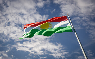 Kurdistan national flag waving at sky background close-up.