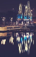 Illuminated port cranes on Lasztownia Island in Szczecin at a foggy night, color toning applied,...