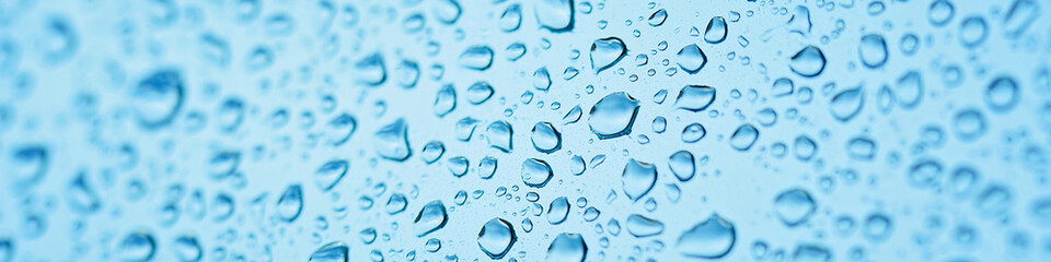 Drops of rain on window glass. Shallow DOF. Natural Blue Water background with Raindrops for sad mood and thoughts. Selective focus