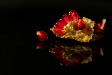 pomegranate seeds on polished granite black background with great reflection