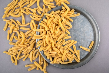 Strozzapreti, Italian pasta in metal plate on a gray table