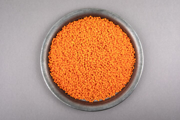Red lentils in a metal plate on a gray table