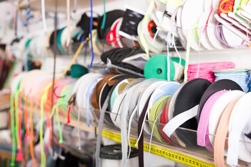 Bobbins with various colorful ribbons on counter in store. Needlework and sewing supplies