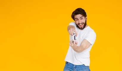 Portrait of his he nice attractive cheerful cheery glad guy playing cool new videogame online isolated over bright vivid shine vibrant yellow color background.