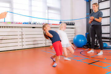 Limbo or laser game for children, little girls having fun in a physical activity class - obrazy, fototapety, plakaty