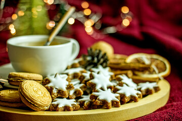 Fototapeta na wymiar Homemade Christmas cookies stars from nuts and dates on a wooden tray, next to a mug of coffee, New Year's decor of pine cones and garlands. Cozy winter tea party, sweet new year food gift