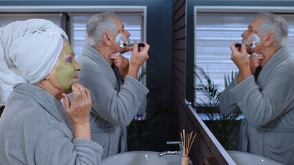 Old senior couple man and woman doing morning hygiene and looking into a mirror. Attractive elderly...
