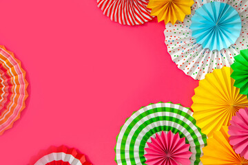 Colorful paper rosette and birthday garlands. Decorating for a party. Round, bright and color decoration. Pink background.