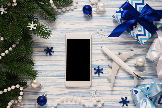 Christmas or New Year travel planning. Mockup blank screen smartphone with plane model for holiday travel. Flat lay top view. Copy space