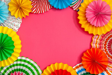 Colorful paper rosette and birthday garlands. Decorating for a party. Round, bright and color decoration. Pink background.