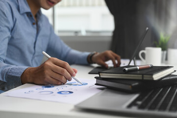 Cropped shot of businessman checking financial report and charts in the office at the workplace.