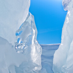 Narrow icy glacier crevasse with snow and blue sky