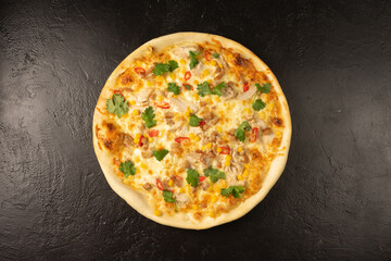 Round hot freshly baked pizza with tuna, olives, dill and cheese lies on a black stone kitchen table