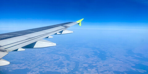 Panorama view of airplane wing, bright blue sky, flight on a passenger plane, view through the porthole, copy space
