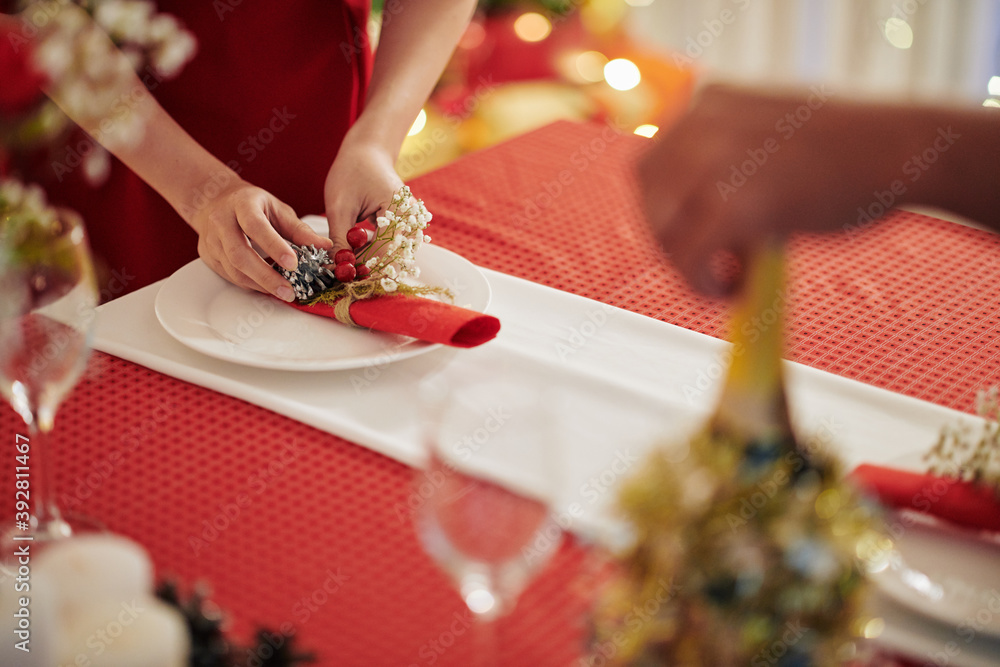 Poster Close-up image of woman putting decorated napkin on table when preparing for Chrismas celebration at home