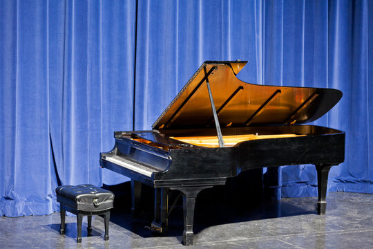 Open grand piano on stage with blue velvet cutain