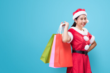 A beautiful woman in Santa Claus costume holding shopping bags on occasion of the Merry Christmas...