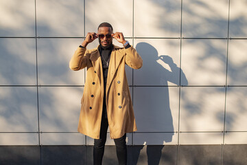 African American man wearing sunglasses posing near building wall