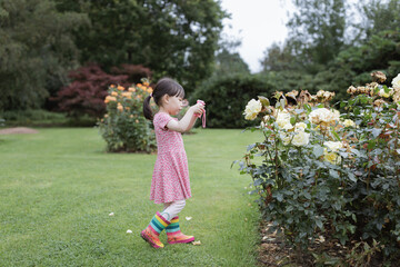 young girl taking photo in the summer garden morning