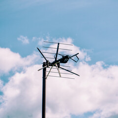 TV antenna on the roof against the blue sky and clouds