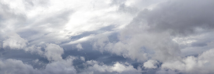 Panorama of the sky with gray rain clouds, through which sunlight barely penetrates