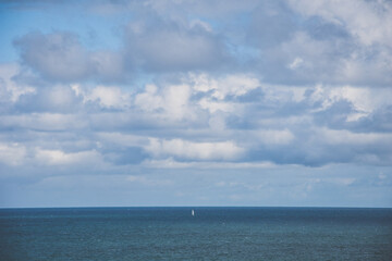 Naklejka na ściany i meble Velero pequeño en medio del mar con nubes