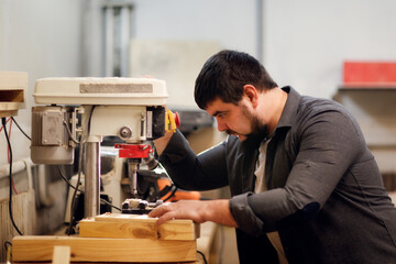 Bearded kraft caucasian man in a carpentry workshop with a drilling machine handcrafted wood board, concept handicraft and craftsmanship close up