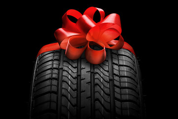 a  black isolation rubber tire, on the grey backgrounds in a bow for christmas