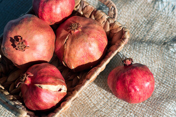 Fall or winter cosy home decoration of pomegranate in natural straw basket on jute cloth...