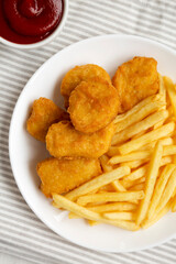 Tasty Fastfood: Chicken Nuggets and French Fries on a plate on cloth, top view. Flat lay, overhead, from above. Close-up.