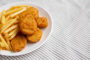 Tasty Fastfood: Chicken Nuggets and French Fries on a plate on cloth, low angle view. Space for text.