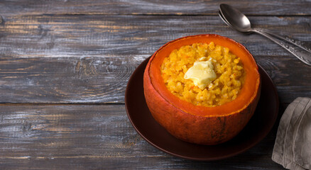 Sweet pumpkin rice with butter baked in pumpkin pot on a wooden table. delicious seasonal homemade breakfast