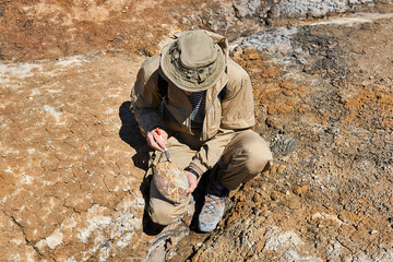 paleontologist brushes a rounded ovoid fossil in a desert