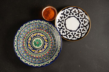 Obraz na płótnie Canvas Ethnic Uzbek ceramic tableware on the black background. Decorative ceramic plate.
