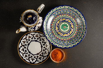Ethnic Uzbek ceramics tableware on the black background. Decorative ceramic with traditional uzbekistan ornament.