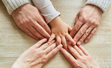 Hand of toddler and hands of adults