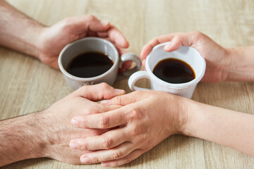 Two hands are touching while drinking coffee