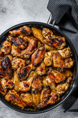 Baked glazed chicken wings in a pan. White background. Top view