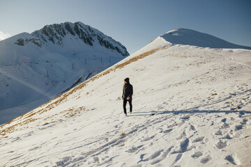 Man is having walk in winter snowy mountain. He feeling freedom and happiness.