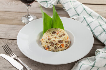 Rice pilau with meat and carrot and glass of red wine on wooden table