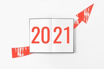 2021 on notebook with red arrow rising up flat lay on white background. New year resolutions. Money, business success. Financial progress. Purpose for 2021. Goals, plans, projects, ideas.