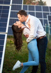 A man kisses his lover against the background of a series of solar panels. A woman with long hair...