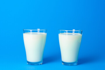 Glass jar with fresh milk against blue background